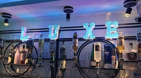 Bar der Luxe Shisha Lounge mit beleuchteten LUXE-Buchstaben und Spirituosen-Regal