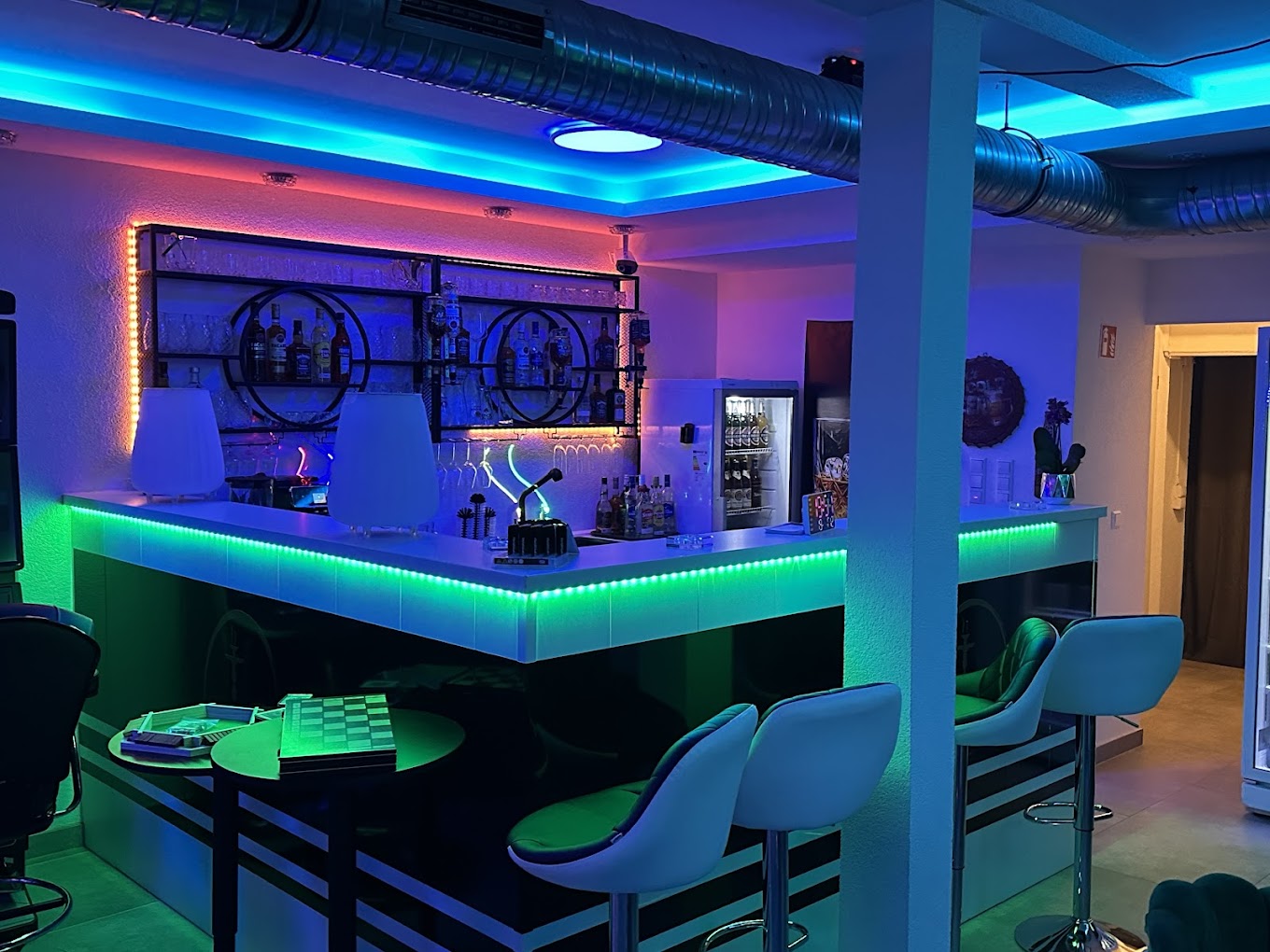 Neon-beleuchtete Bar der Luxe Shisha Lounge mit Spirituosen und Barhockern